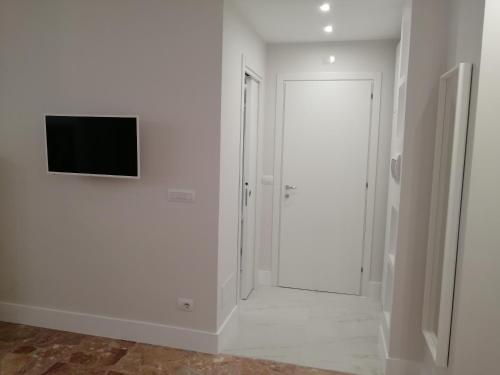 a white hallway with a door and a television on a wall at Insieme al mare in Praia a Mare