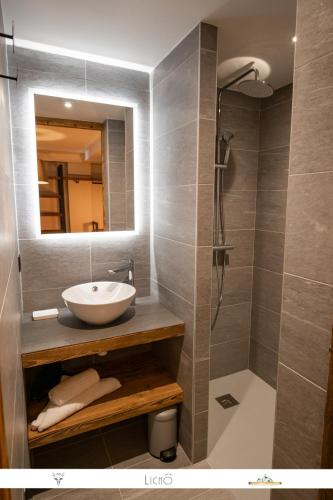 une salle de bain avec un lavabo et une douche avec un miroir dans l'établissement Marmotte 103 - Luxueux appartement aux pieds des pistes, à Bonneval-sur-Arc