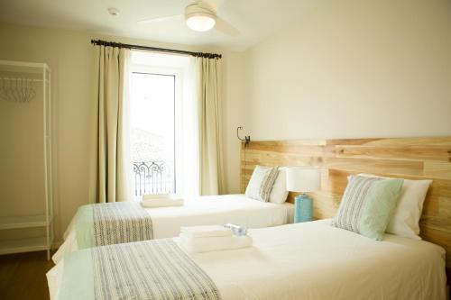 two beds in a room with a window at THE HOLY COW - Hostel & Suites in Ponta Delgada