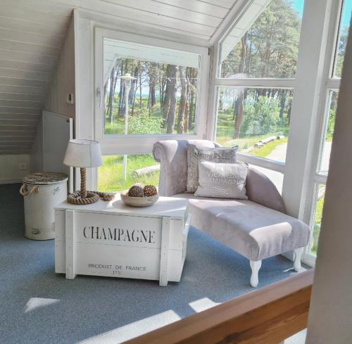 a living room with a chair and a table and window at Strandhaus Rügen - Meerblick, Sauna, Kamin & Whirlpool in Baabe