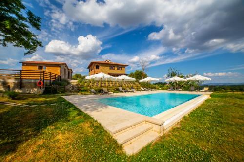 una piscina con ombrelloni e una casa sullo sfondo di Terra Antica Apartments - La Fornace a Montepulciano