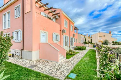 una vista exterior de un edificio rosa con un camino en Medulin Luxury Apartments with beautiful garden 100 m from beach en Medulin
