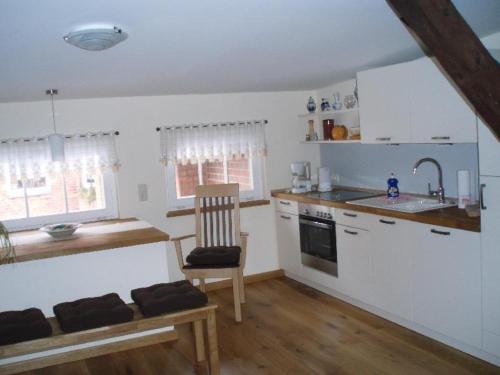 a kitchen with white cabinets and a chair and a sink at Stadtferienwohnung in Teterow