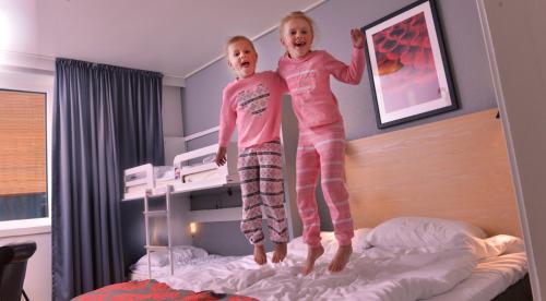 2 enfants sont debout au-dessus d'un lit dans l'établissement Scandic Meyergården, à Mo i Rana