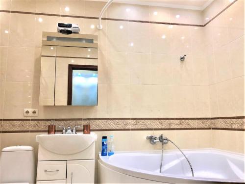 La salle de bains est pourvue d'une baignoire, d'un lavabo et d'un miroir. dans l'établissement VIP апартаменти з видом на озеро, à Kiev