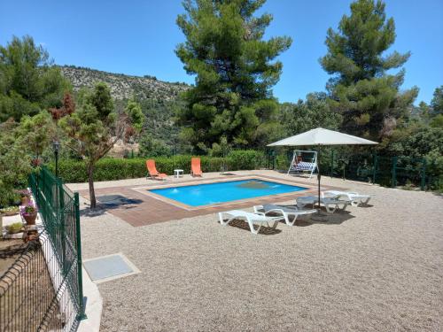 una piscina con ombrellone, tavolo e sedie di La Pedrera a Beceite