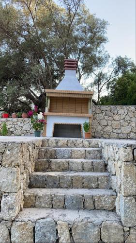 a stone retaining wall with a stone stairway with a building at Elina's Maisonette in Episkopos