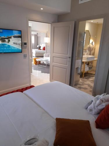 a bedroom with a large white bed and a living room at Mas des Herbes Blanches Hôtel & Spa – Relais & Châteaux in Joucas