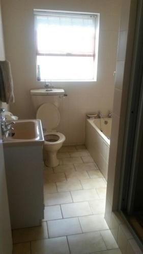a bathroom with a toilet and a sink and a tub at Lagoon Edge in Hermanus