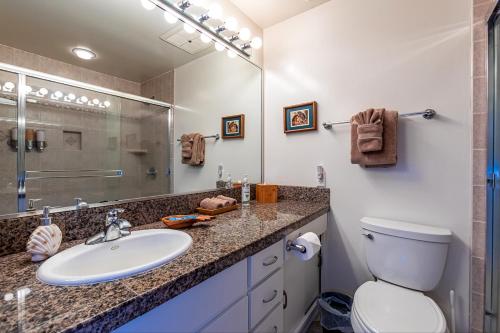 a bathroom with a sink and a toilet and a mirror at Wailea Sunset Condo - Ekolu #607 in Wailea