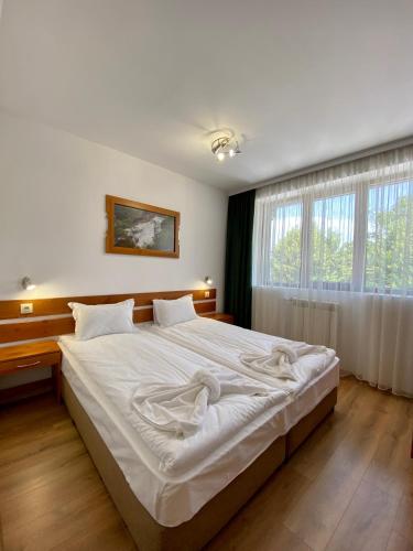a large white bed in a room with a window at Edelweiss Central Hotel in Bansko