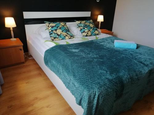 a large bed with a green blanket and two pillows at Apartament M-3 in Częstochowa