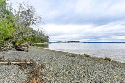 a beach with a tree on the shore of a body of water at Octopus Den in Coupeville