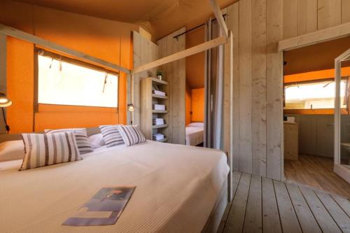 1 dormitorio con cama blanca y pared de color naranja en Camping Fayón Fishing, en Fayón