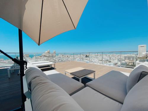 balcón con mesa, sillas y sombrilla en Skyline - Penthouse with 50m2 private terrace and stunning views, en Cádiz