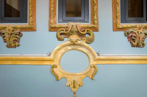 a gold mirror on a wall with two frames at Hotel Palacio La Marquesa 4 Estrellas SUP in Teruel