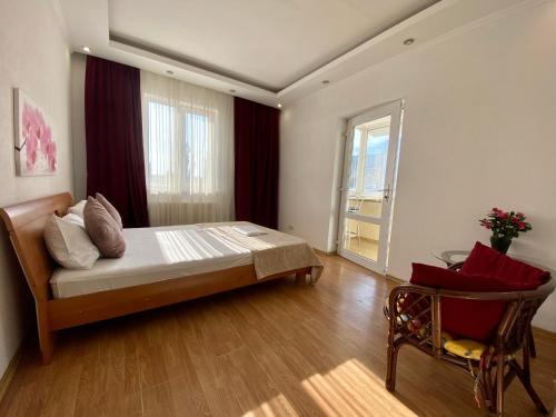 een slaapkamer met een bed, een stoel en een raam bij Central Apartments in Odessa