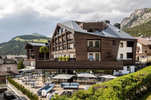 ein Gebäude mit Stühlen und Sonnenschirmen davor in der Unterkunft Linder Cycling Hotel in Wolkenstein in Gröden