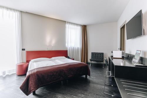 a bedroom with a bed with a red headboard and a desk at Hotel Continental in Cremona