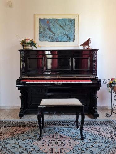 a black piano with a bench in a room at Hotel La Terrazza in Porto San Giorgio