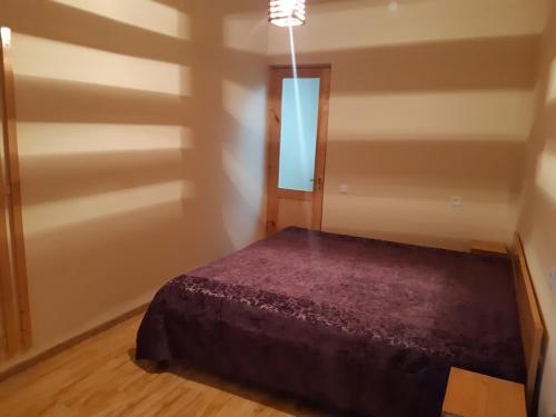 a bedroom with a bed with a purple comforter at Andranik B&B in Goris