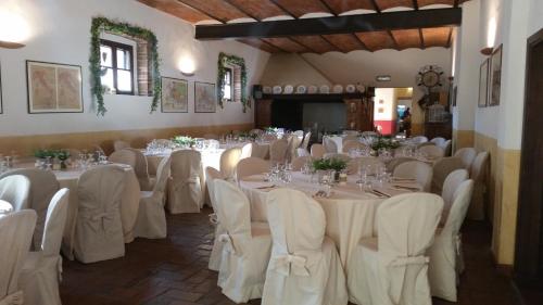 um salão de banquetes com mesas e cadeiras brancas em Agriturismo San Galgano em Chiusdino