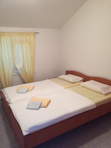 a bedroom with two beds with white sheets and a window at Apartmani Dora in Vodice
