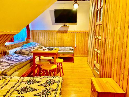 a room with two beds and a table and a tv at Pokoje Gościnne u Marysi in Białka Tatrzańska