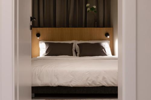 een slaapkamer met een wit bed en een houten hoofdeinde bij Apartman Mali raj in Pakoštane
