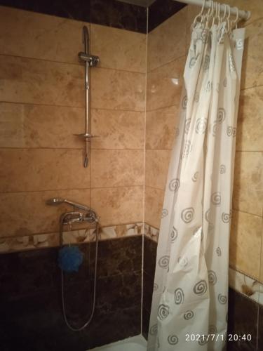 a shower with a white shower curtain in a bathroom at У Марка in Volosyanka