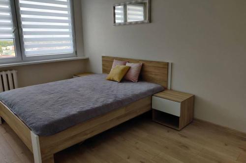 a bedroom with a wooden bed with two pillows at Apartament Na 8 Piętrze in Płock