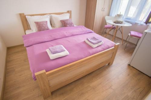 a bedroom with a large bed with a pink blanket at Apartmani ALBION in Žabljak