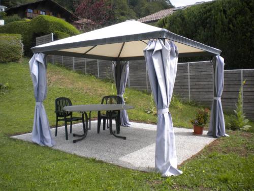 un cenador con una mesa y sillas debajo en Appartement La Coudraie, en Blonay