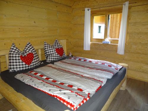 Una cama en una cabaña de madera con almohadas. en C.T.N. Loghouse, en Hallstatt