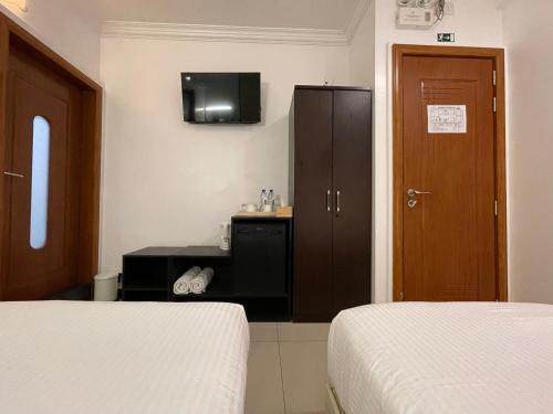 a bedroom with two beds and a tv and a cabinet at Huvan Beach Hotel at Hulhumale in Hulhumale