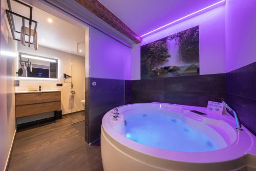 La salle de bains est pourvue d'une grande baignoire avec un éclairage violet. dans l'établissement Boutique Hotel Scheepers, à Fauquemont