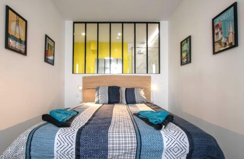 - une chambre avec un lit doté d'oreillers bleus et d'une fenêtre dans l'établissement Chez Emile Le Jaune Vendée - T2 renové - Terrasse, à Niort