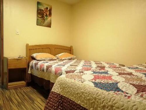 a bedroom with two beds with a quilt on it at Hostal Inca in San Pedro