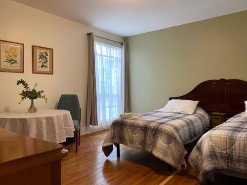 a bedroom with a bed and a table and a window at Nebraska Suites WTC in Mexico City