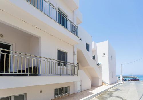 a white building with balconies on a street at Sole Mare Seaside Apartments in Gouves