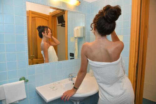 a woman standing in a bathroom looking at herself in the mirror at Hotel Pineta in Ischia