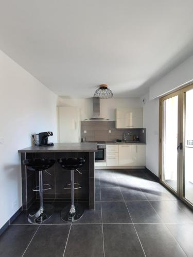 une cuisine avec un comptoir et deux tabourets de bar dans l'établissement Spacieux T2 lumineux proche du centre, à Ajaccio