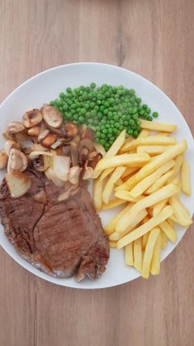 a plate of food with meat and chips and peas at Sycamore House in Laurière
