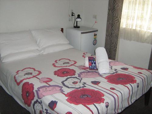 a bed with a white comforter and pillows on it at Kookaburra Inn in Brisbane