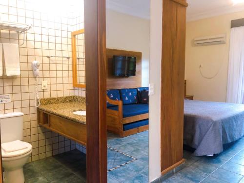 uma casa de banho com uma cama, um lavatório e um WC. em Suíte 1210 em Flat frente ao mar em Ilhabela