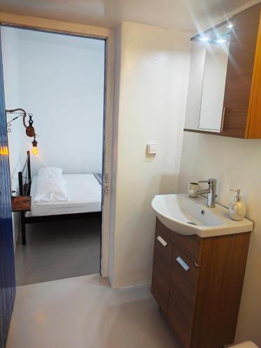 a bathroom with a sink and a bedroom with a bed at Prickly Pear House in Plaka Milou