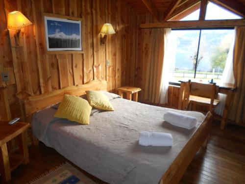 a bedroom with a bed in a wooden room at Hosteria-Cabañas Rucapillan in Choshuenco