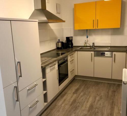 a kitchen with white and yellow cabinets and wooden floors at Ferienwohnungen am Feldrain - Gornau im Erzgebirge in Zschopau