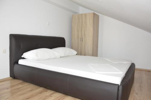 a bed with a black headboard and white pillow at Apartman 2 in Senj