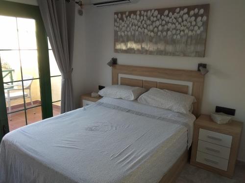 a bedroom with a white bed and a balcony at Captivating Duplex on the Castillo Mar Complex in Caleta De Fuste